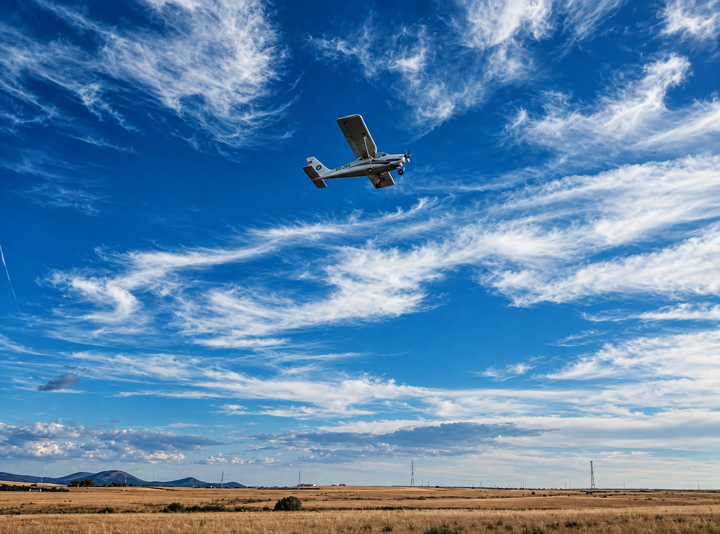 Avioneta volando bajo cielo azul con nubes sobre los campos de Segovia