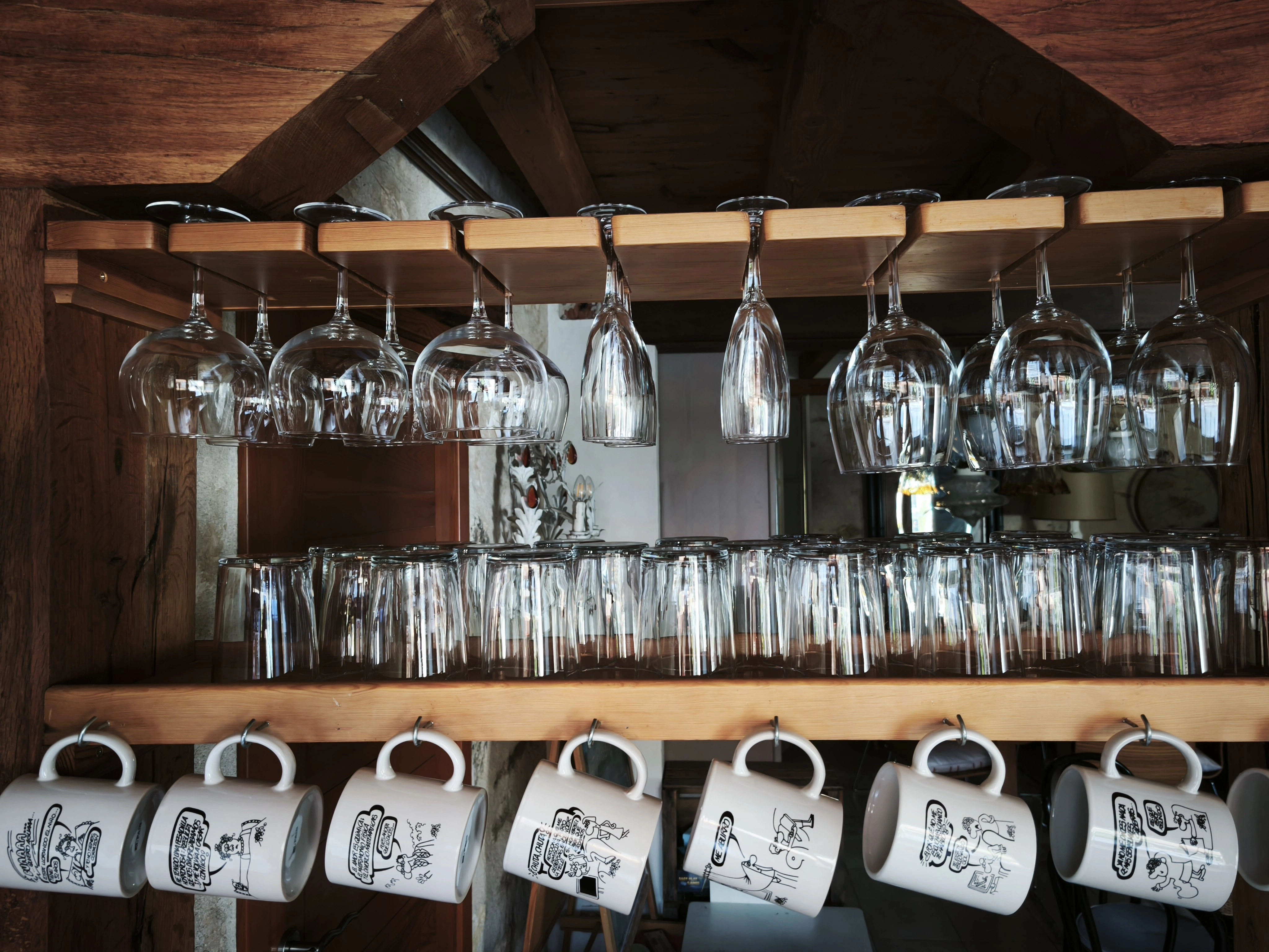 Copas de cristal y tazas ilustradas en la cocina de la casa rural