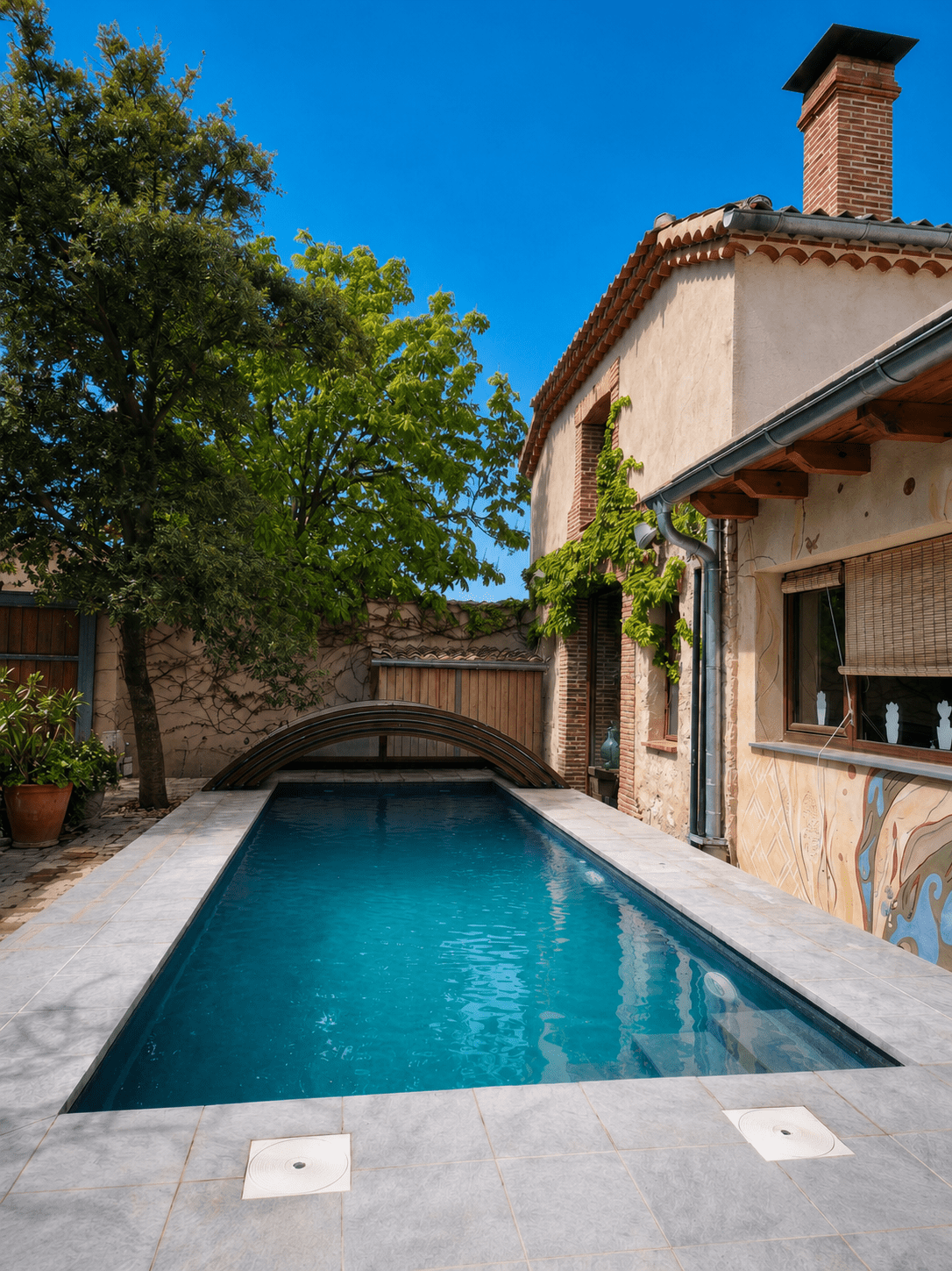 Piscina climatizada con cubierta junto a la fachada de piedra de la casa rural