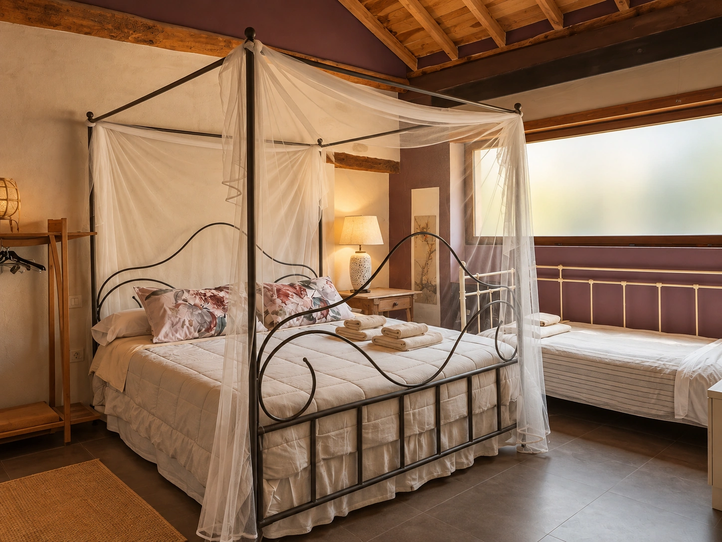 Suite con cama con dosel de forja y cortinas blancas en Viento de Ladera